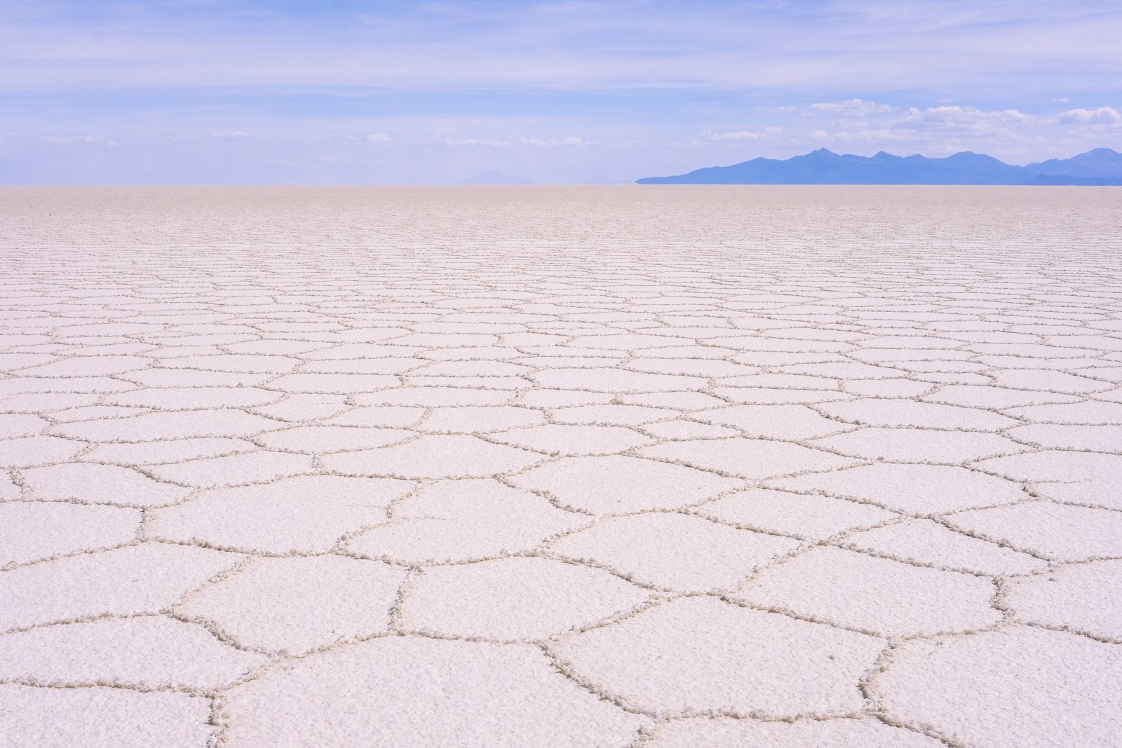 A vast expanse of white sand with mountains in the distance